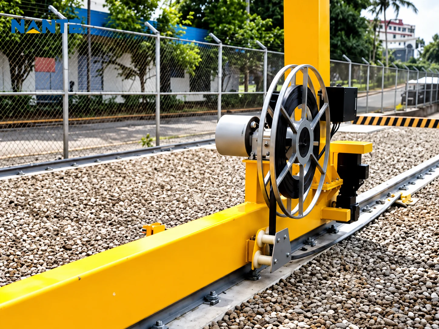 Crane cable reel installed on a yellow runway structure beside travel rails