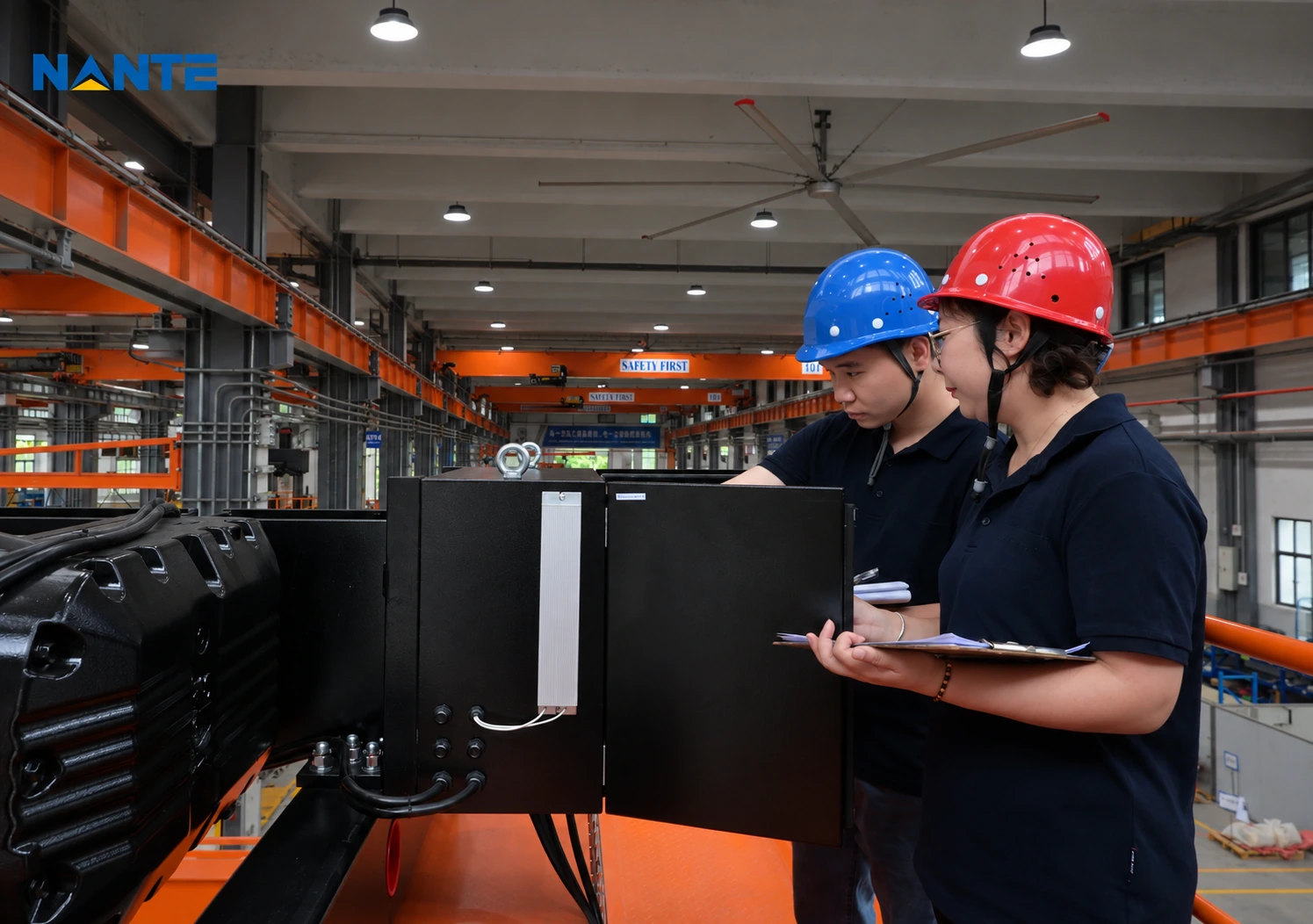 Two technicians examining a crane component and reviewing paperwork in a workshop